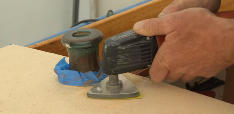 A trim sander will be able to get closer to deck-mounted hardware than a disc or random-orbital sander.
