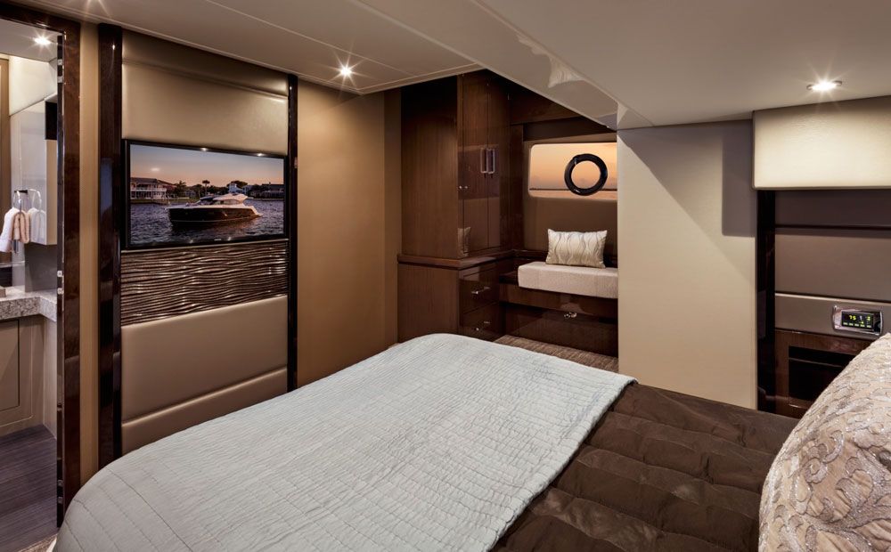 Dark tan upholstery and wall coverings along with dark, rich, glossy cabinetry give the master stateroom a luxurious and modern vibe.