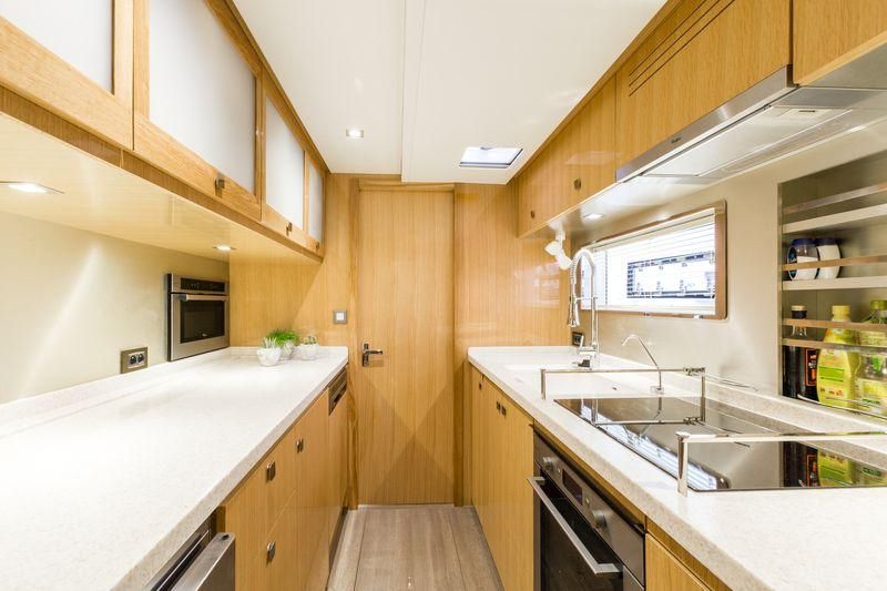 The galley features a large glass cooktop outboard, flanked on one side by a house-sized sink and on the other by ample countertops laid over numerous cupboards and soft-close drawers.