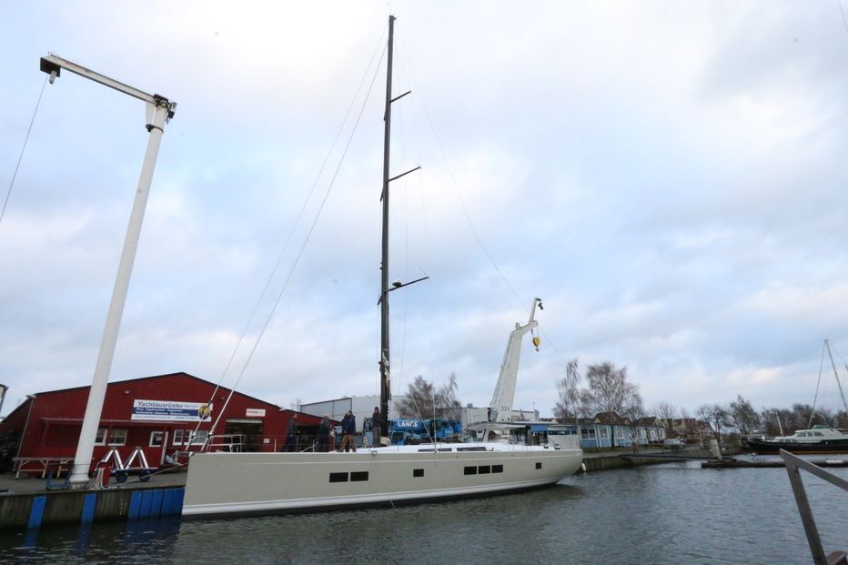 Der gestellte Mast überragt Schiff und Werft