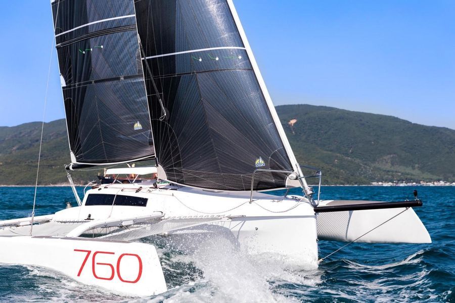 Un Corsair 760 blanc de côté navigue sur l'océan avec des montagnes en arrière-plan par une journée claire.