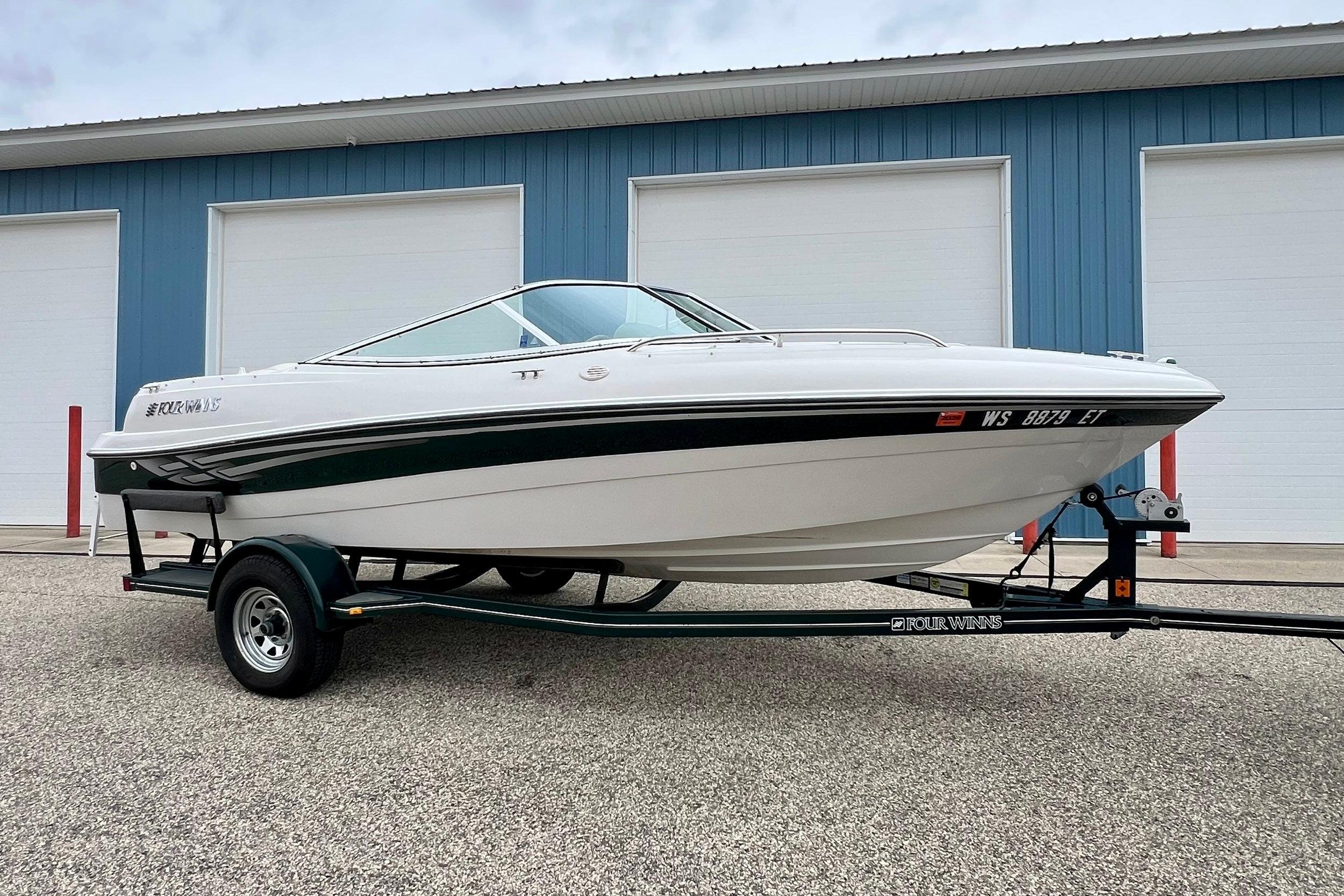 Four Winns 190 HORIZON SS 2000 Four Winns 190 Horizon SS boat on trailer, parked near blue building.