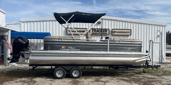 Sun Tracker Party Barge 22 RF DLX 2023 Sun Tracker Party Barge 22 RF DLX pontoon boat on trailer outside dealership.