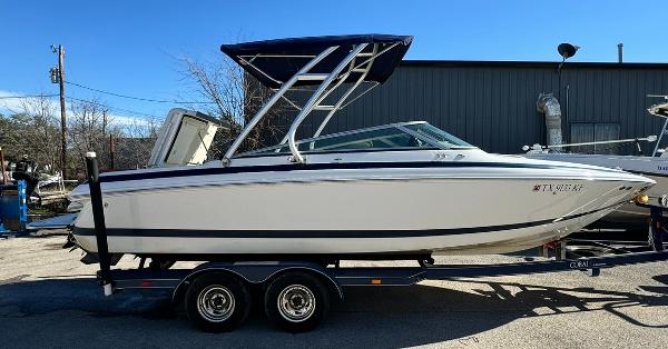 Cobalt 246 2005 Cobalt GS242 boat on trailer, parked outdoors under clear blue sky.