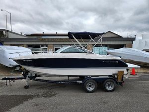 Four Winns 215 Sundowner 2013 Four Winns 215 Sundowner boat on trailer, parked outside a building under cloudy skies.