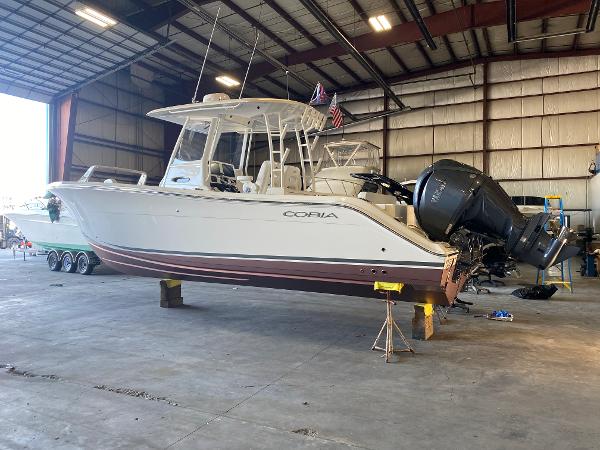 Cobia 301 Center Console 2021 Cobia 301 Center Console boat in a warehouse, elevated on supports.