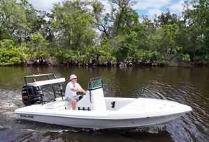 Action Craft 17 Flats 2025 Action Craft 17 Flats boat cruising on a calm river with lush greenery.