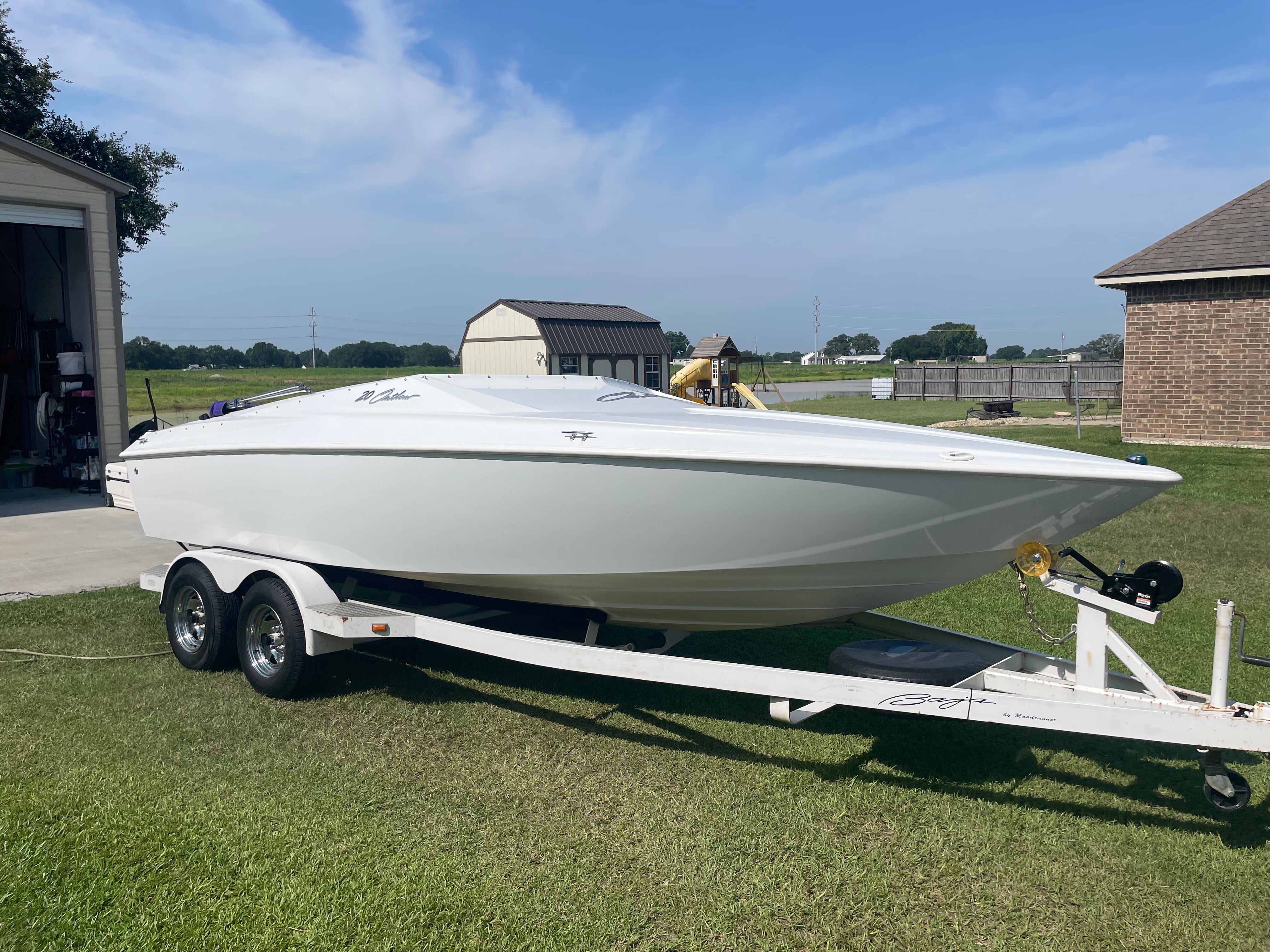 Baja 20 Outlaw 2002 Baja 20 Outlaw speedboat on trailer, parked on grass near buildings.