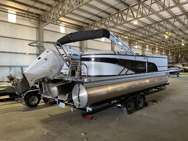 Crest Classic DLX 240 2023 Crest Classic DLX 240 pontoon boat in a spacious indoor storage facility.