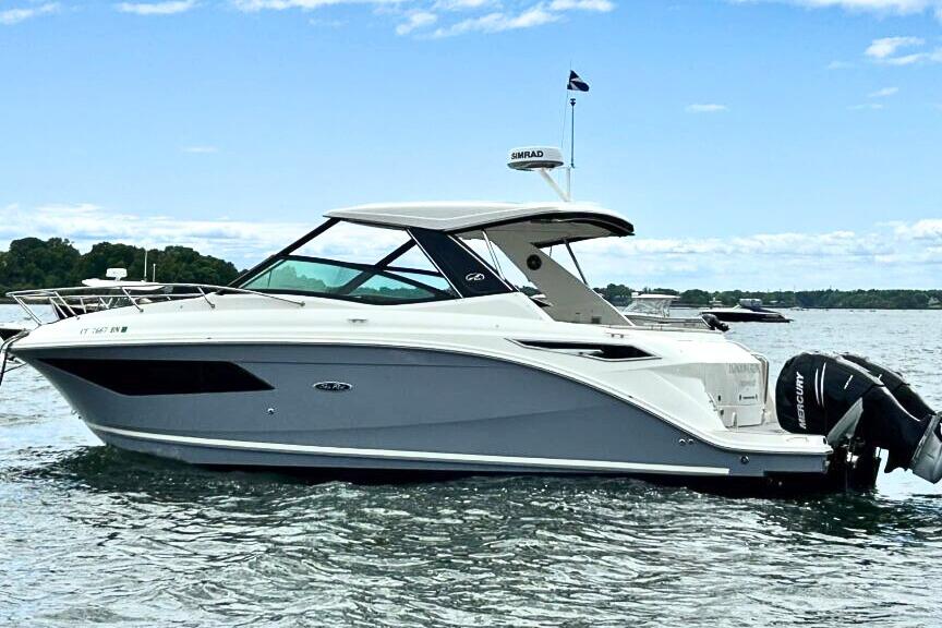 Sea Ray 320 Sundancer 2021 Sea Ray 320 Sundancer boat on calm water under a clear blue sky.