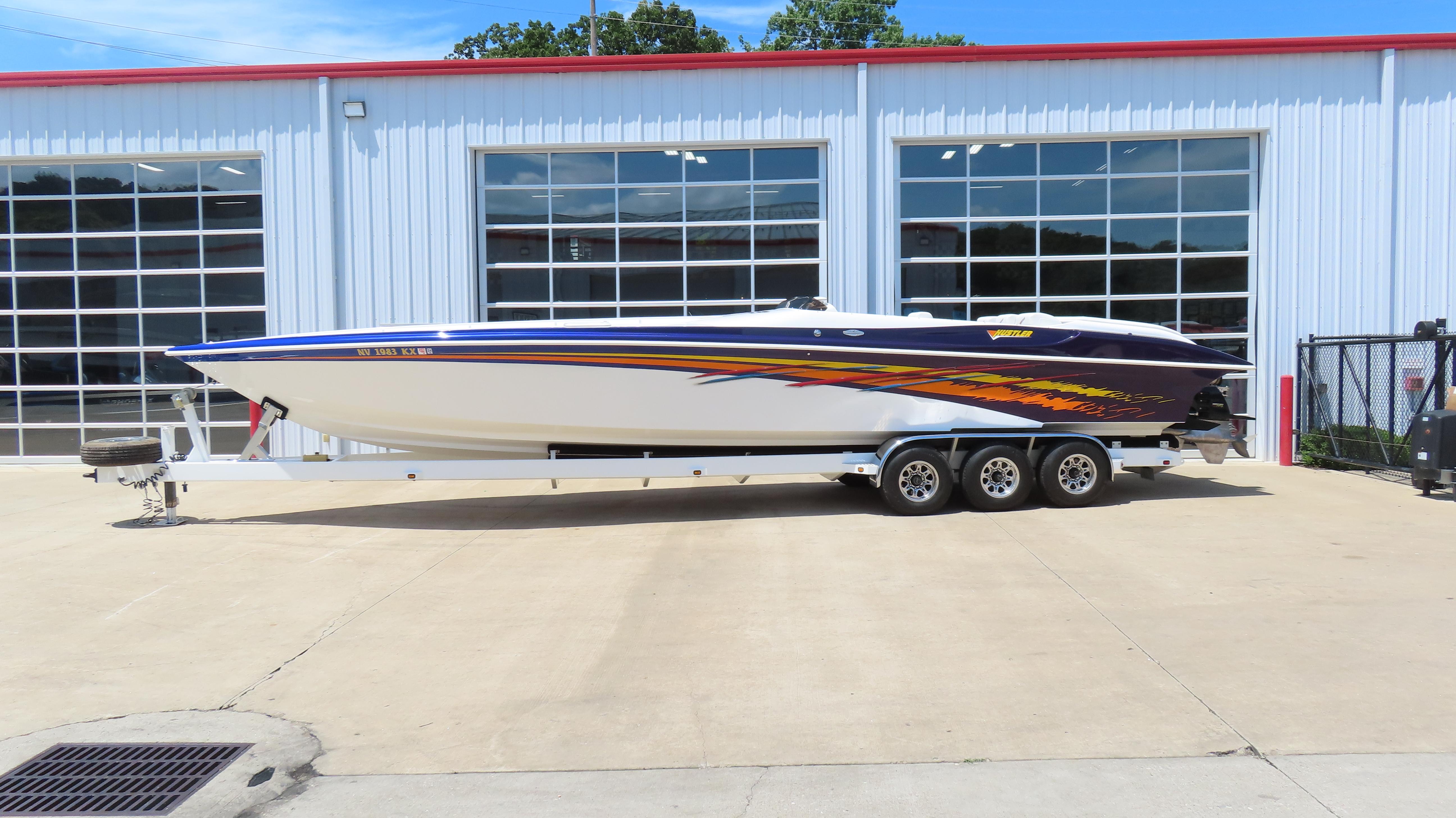 Hustler 388 SLINGSHOT 1998 Hustler 388 SLINGSHOT speedboat on trailer, parked outside a garage.