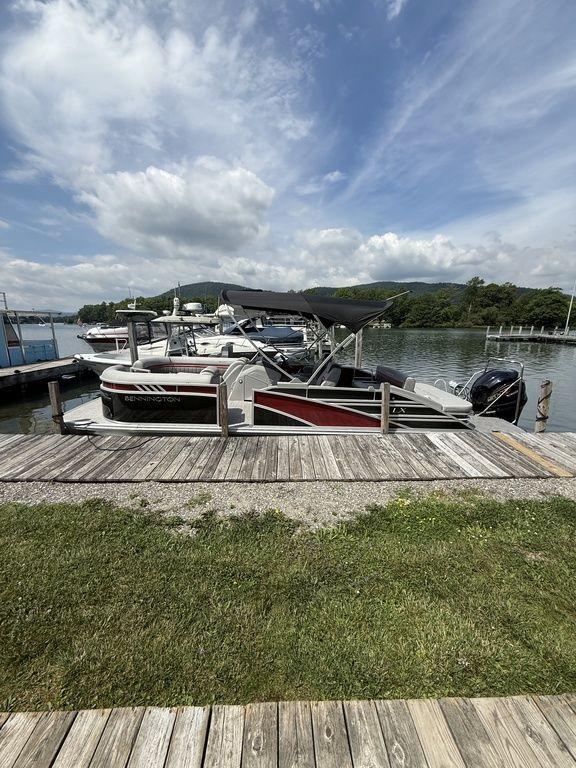 Bennington 24 LXSSB 2024 Bennington 24 LXSSB pontoon boat docked by a scenic lake under a cloudy sky.