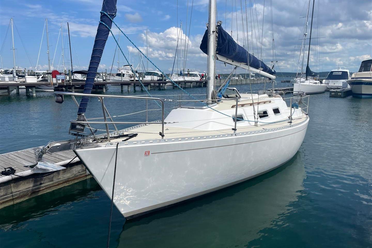 J Boats J/28 1986 J Boats J/28 sailboat docked in a marina under a partly cloudy sky.