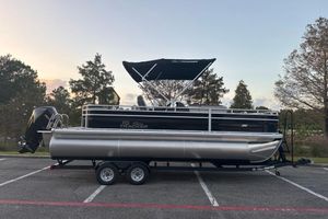 Sun Tracker Fishin' Barge 22 XP3 2026 Sun Tracker Fishin' Barge 22 XP3 pontoon boat on trailer, parked outdoors.