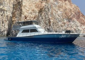 Viking 58 Convertible 1991 Viking 58 Convertible yacht near rocky cliffs on clear blue water.