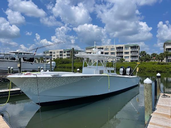 Custom Carolina Irving Forbes 2023 Custom Carolina Irving Forbes boat docked at marina with blue sky and clouds.