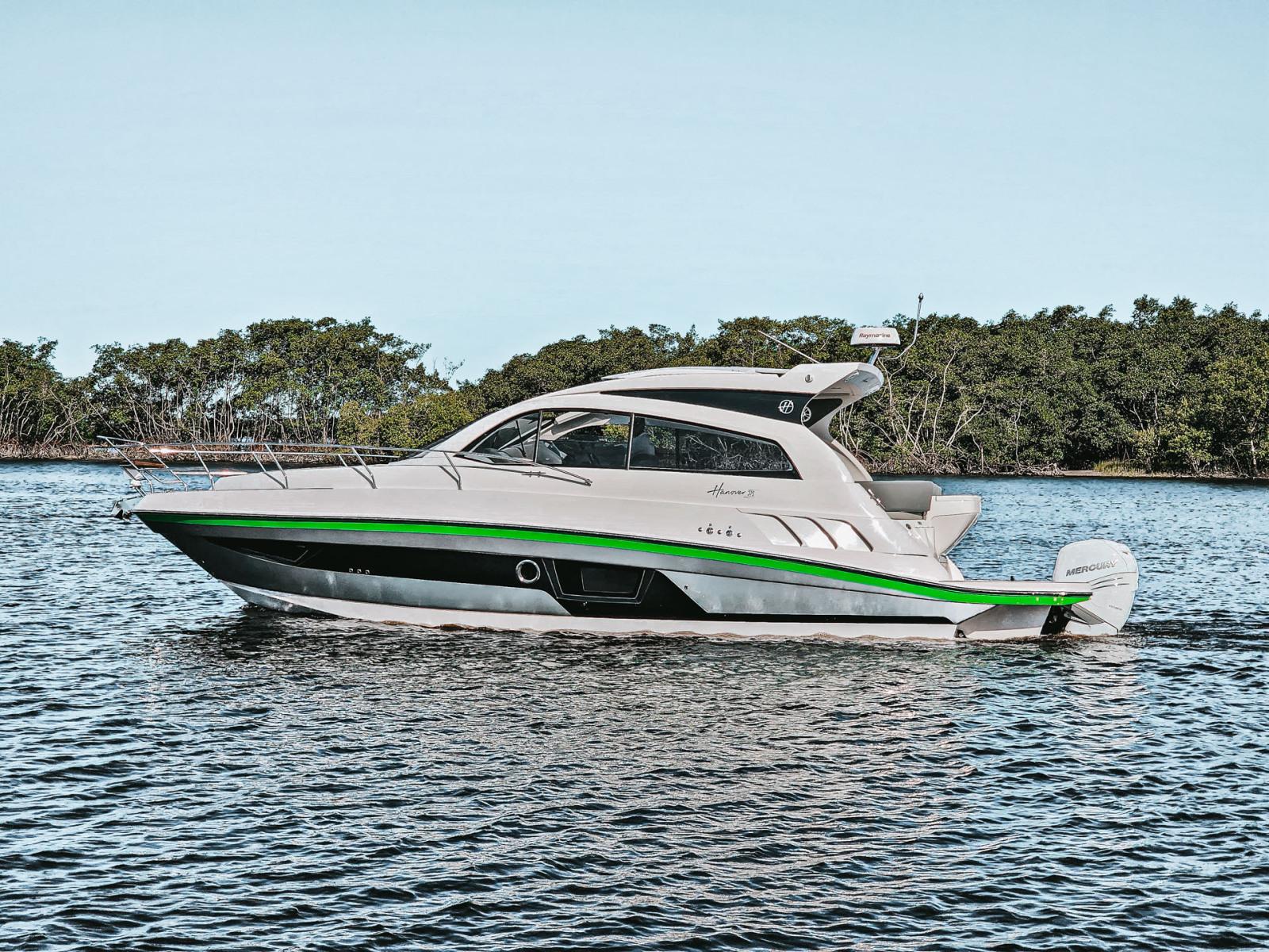 Hanover 375 Outboard 2025 Hanover 375 Outboard boat cruising on a calm lake with lush greenery.