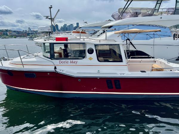 Ranger Tugs R-25 2021 Ranger Tugs R-25 boat, red and white, docked in a marina.