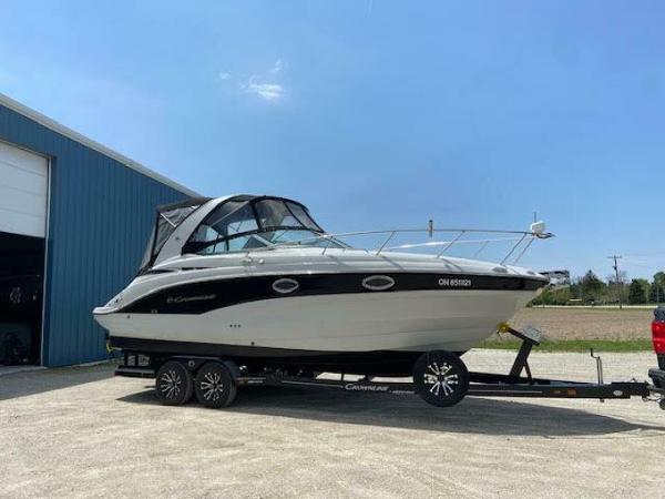 Crownline 264 CR 2023 Crownline 264 CR boat on trailer near blue building under clear sky.