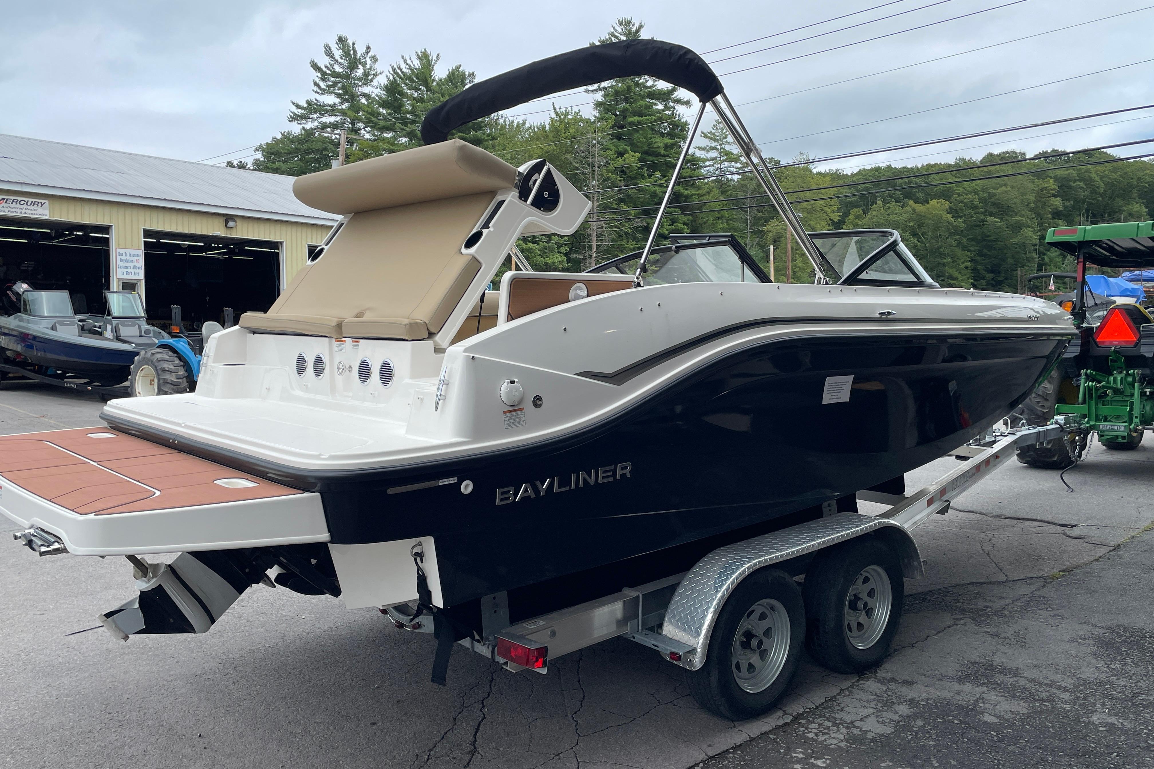 Bayliner DX 2050 2024 Bayliner DX 2050 boat on trailer, parked outdoors near a building.