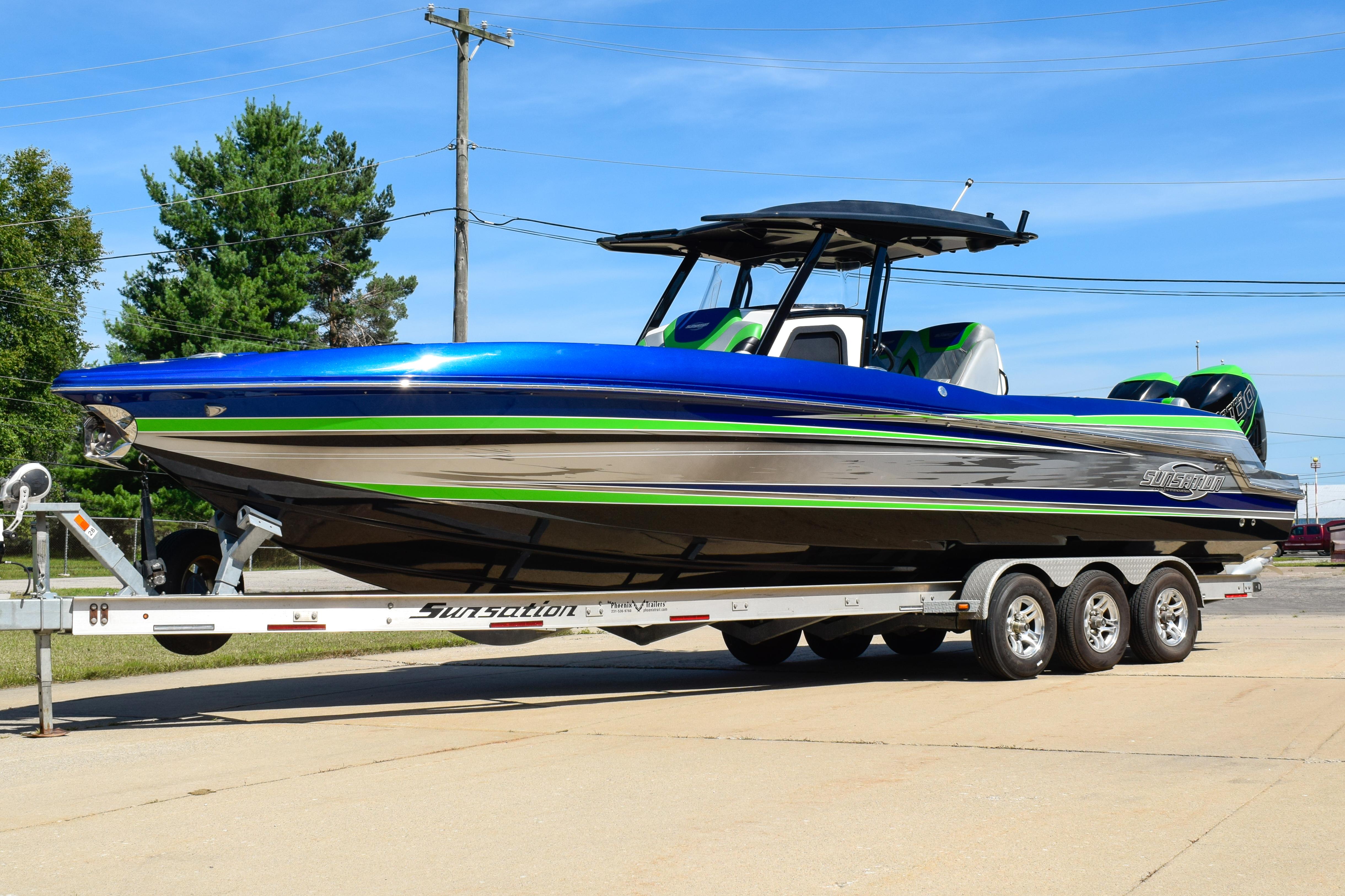 Sunsation 32 CCX 2018 Sunsation 32 CCX boat on trailer, blue and green accents, parked outdoors.