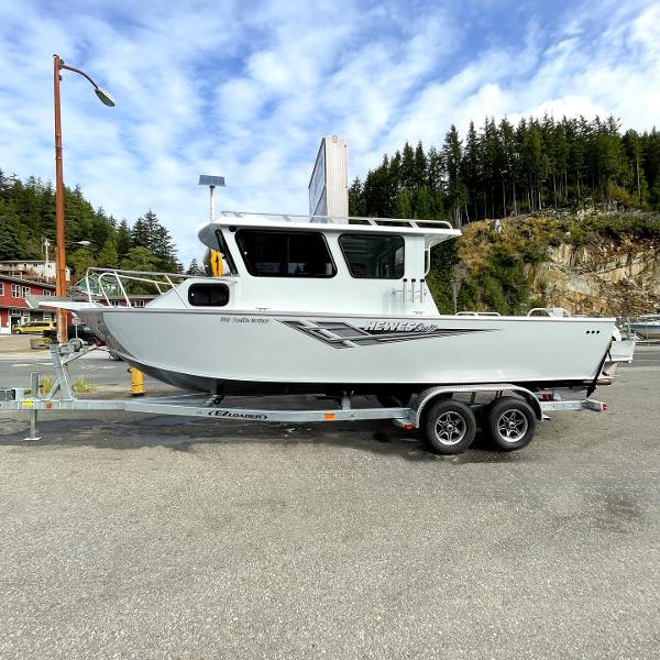 Hewescraft 240 Pacific Cruiser 2024 Hewescraft 240 Pacific Cruiser boat on a trailer in a scenic outdoor setting.