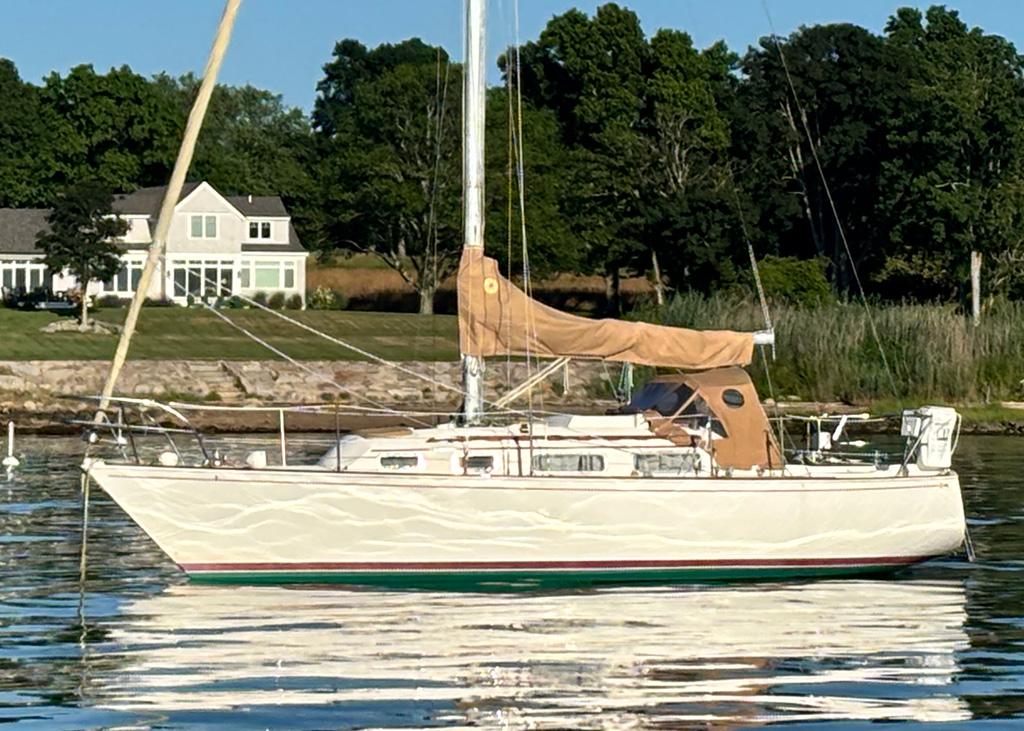 Sabre 30 1981 Sabre 30 sailboat anchored near a shoreline with trees and a house.