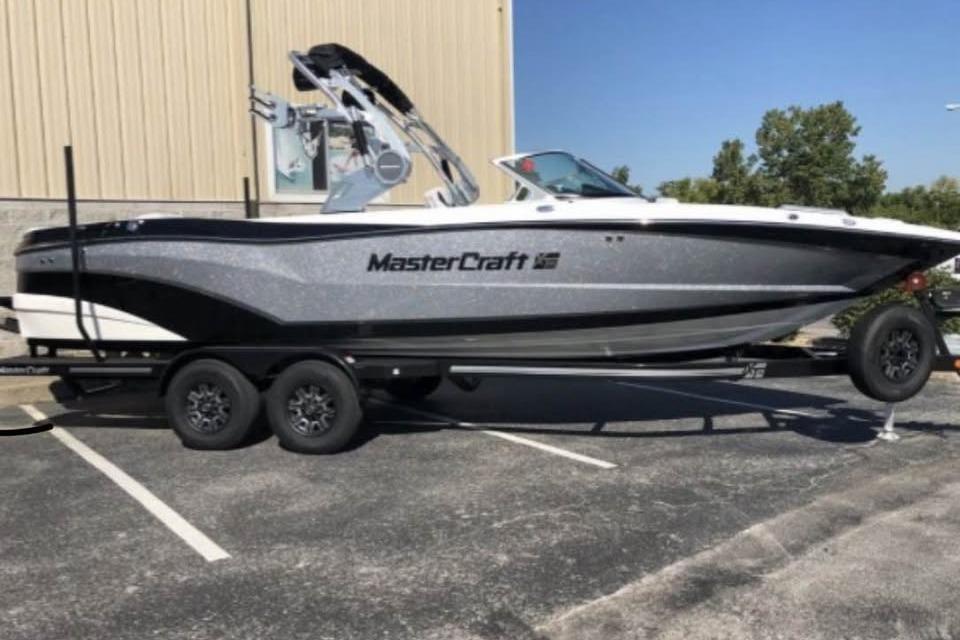 MasterCraft XT25 2019 MasterCraft XT25 boat on trailer in parking lot, side view.