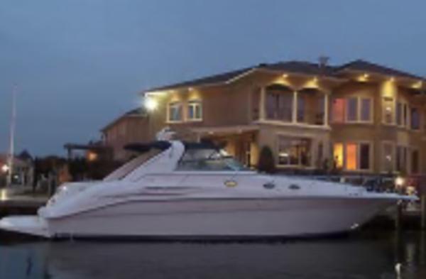 Sea Ray 450 Sundancer 1996 Sea Ray 450 Sundancer yacht docked near a luxurious waterfront home at dusk.