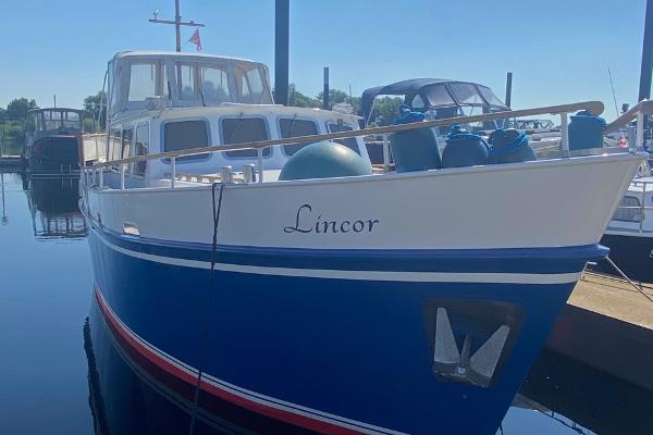 Kotter jebe Blue and white 1982 Kotter Jebe boat named "Lincor" docked at a marina.