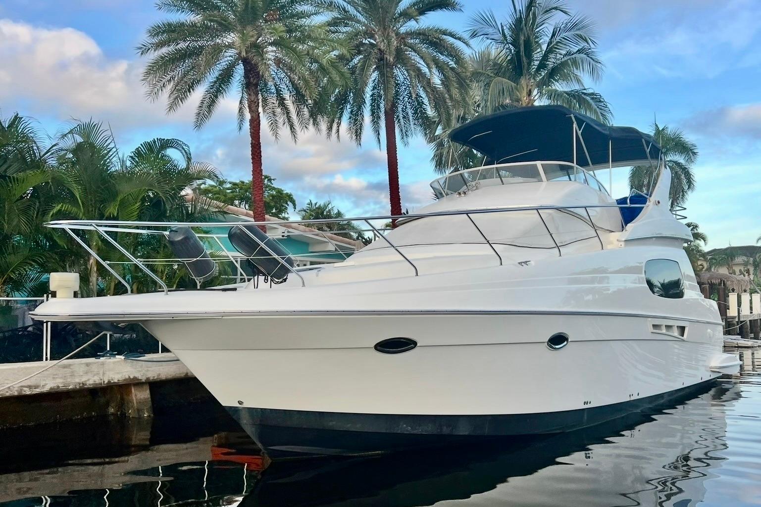 Silverton 410 Sport Bridge 2001 Silverton 410 Sport Bridge yacht docked near palm trees, reflecting on water.