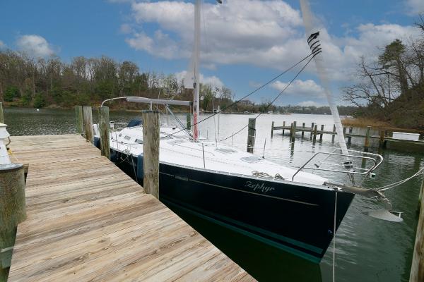 Beneteau 393 2002 Beneteau 393 sailboat docked by a wooden pier on a calm lake.