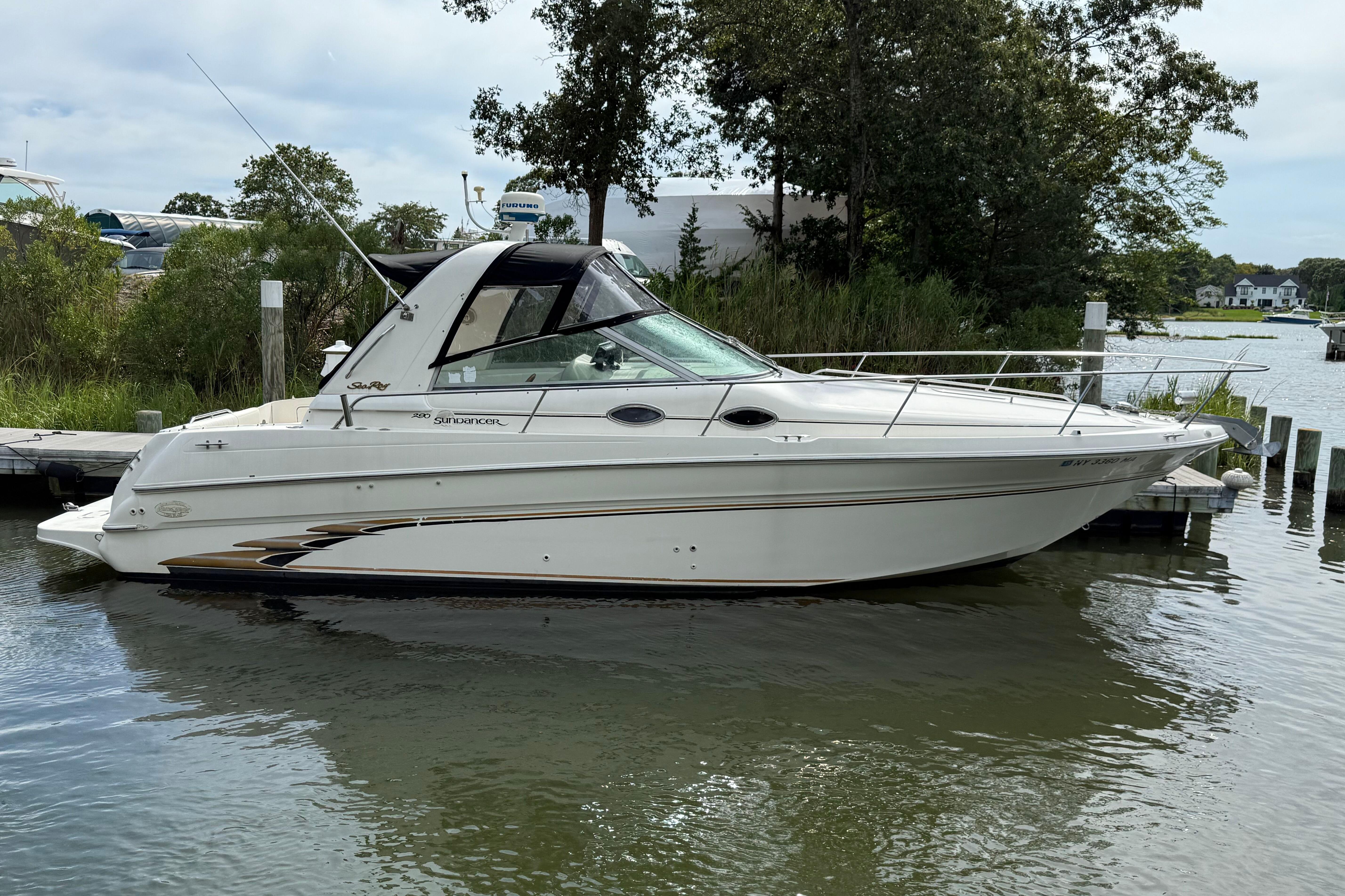 Sea Ray 290 Sundancer 1998 Sea Ray 290 Sundancer boat docked on a calm river with lush greenery.