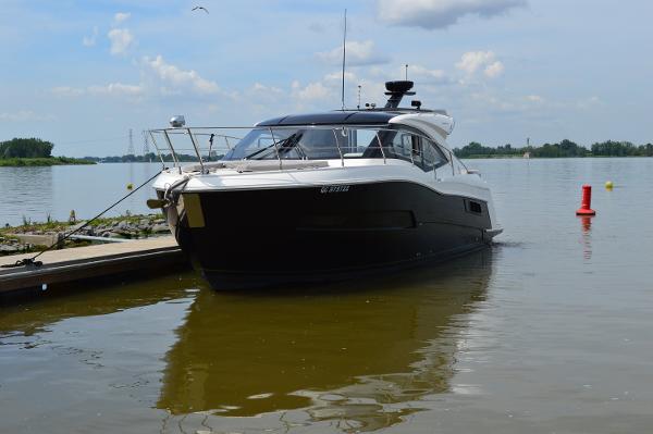 Carver 37 COUPE 2021 Carver 37 COUPE yacht docked on a calm lake under a partly cloudy sky.