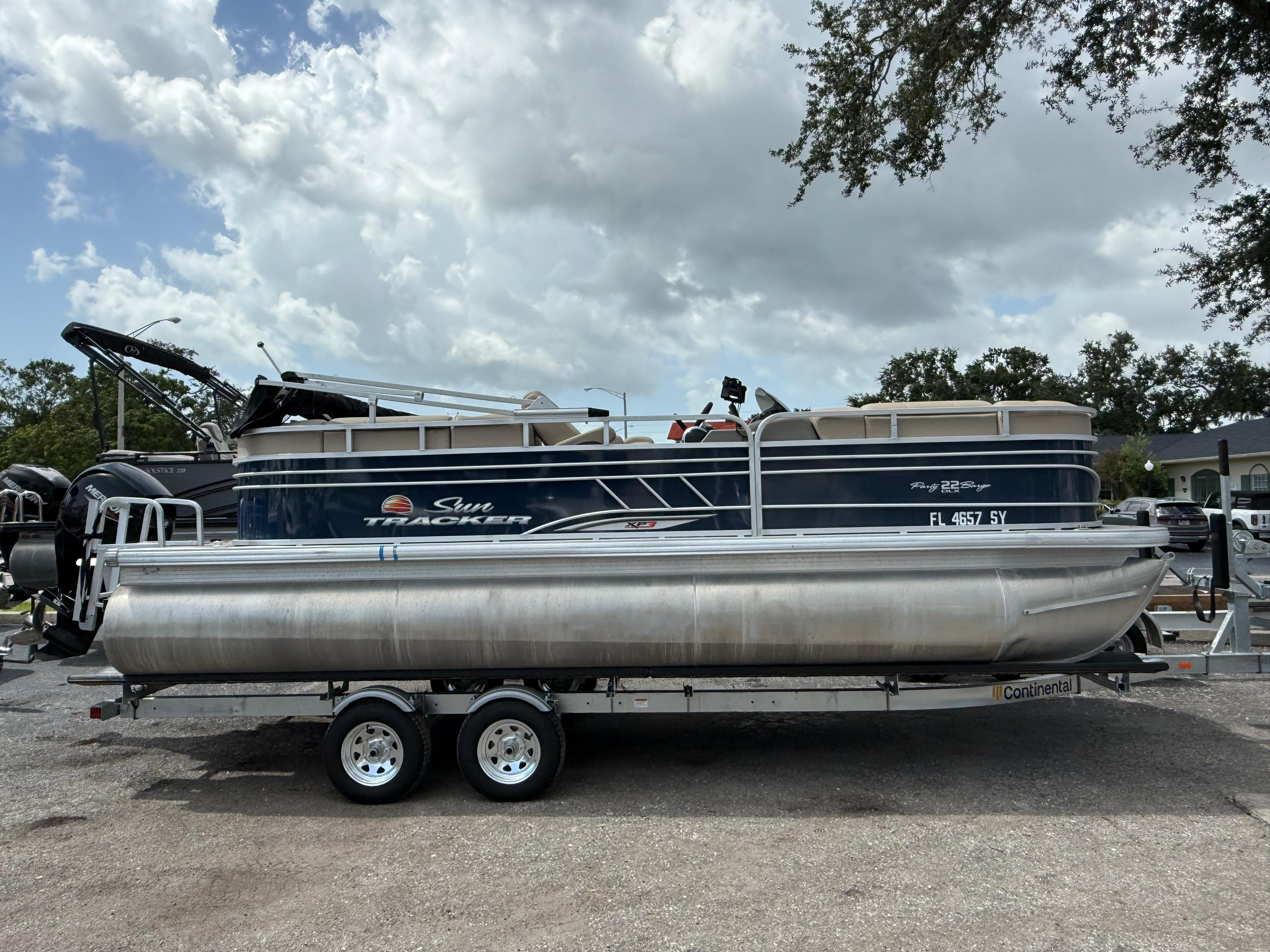 Sun Tracker Party Barge 22 DLX 2021 Sun Tracker Party Barge 22 DLX pontoon boat on trailer, parked outdoors.