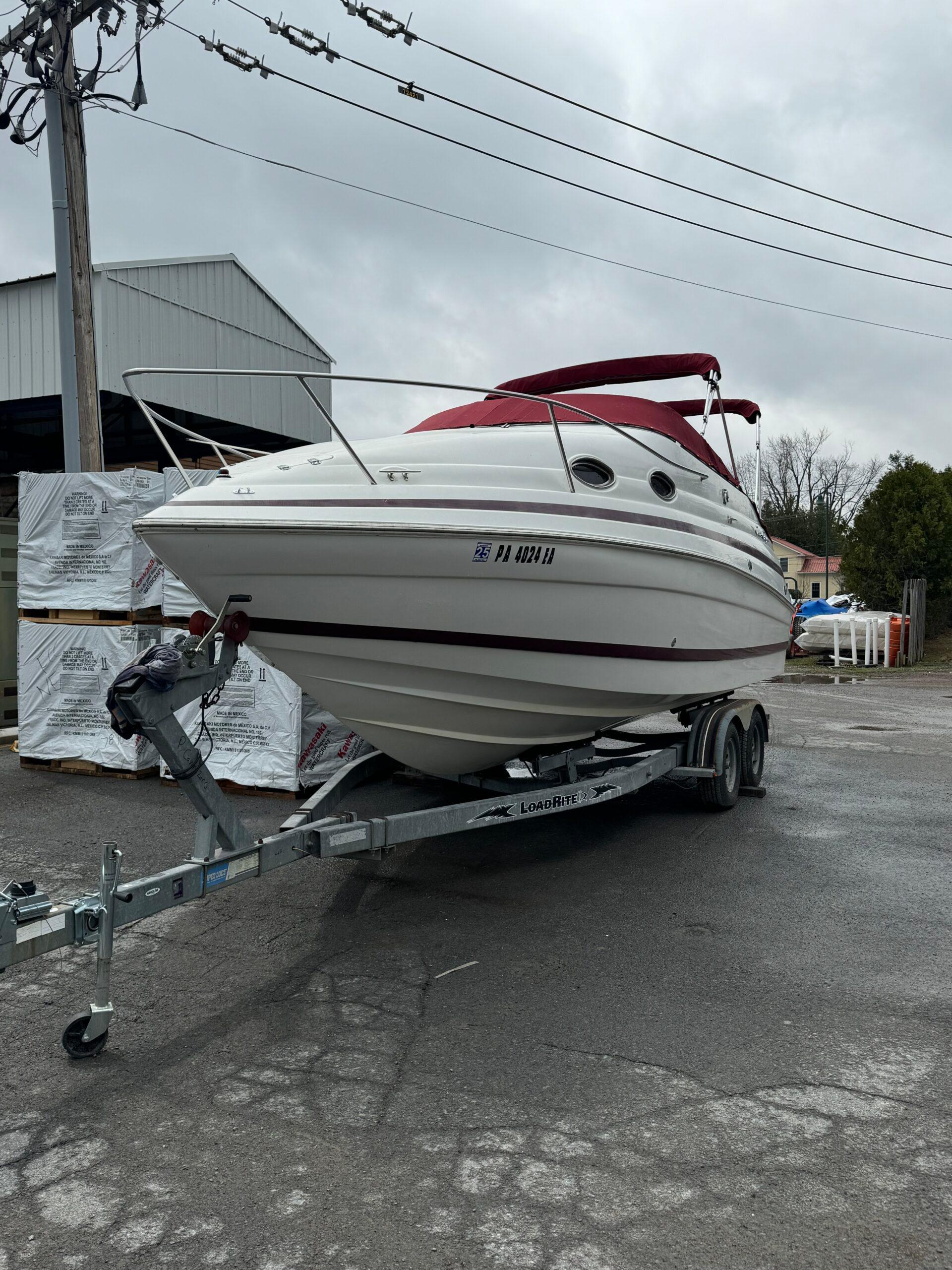 Chris-Craft 24 1999 Chris-Craft 24 boat on trailer with red canopy, parked outdoors.