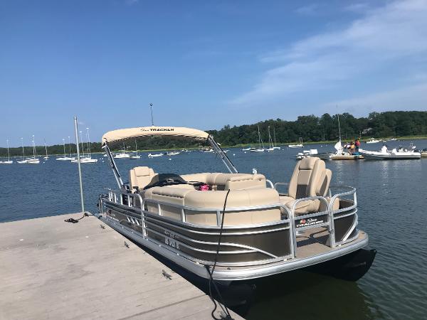 Sun Tracker SportFish 20 DLX 2023 Sun Tracker SportFish 20 DLX pontoon boat docked on a sunny lake.