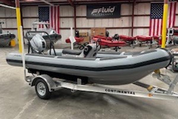 Fluid Watercraft Patrol 16 2025 Fluid Watercraft Patrol 16 boat on trailer in warehouse with American flags.