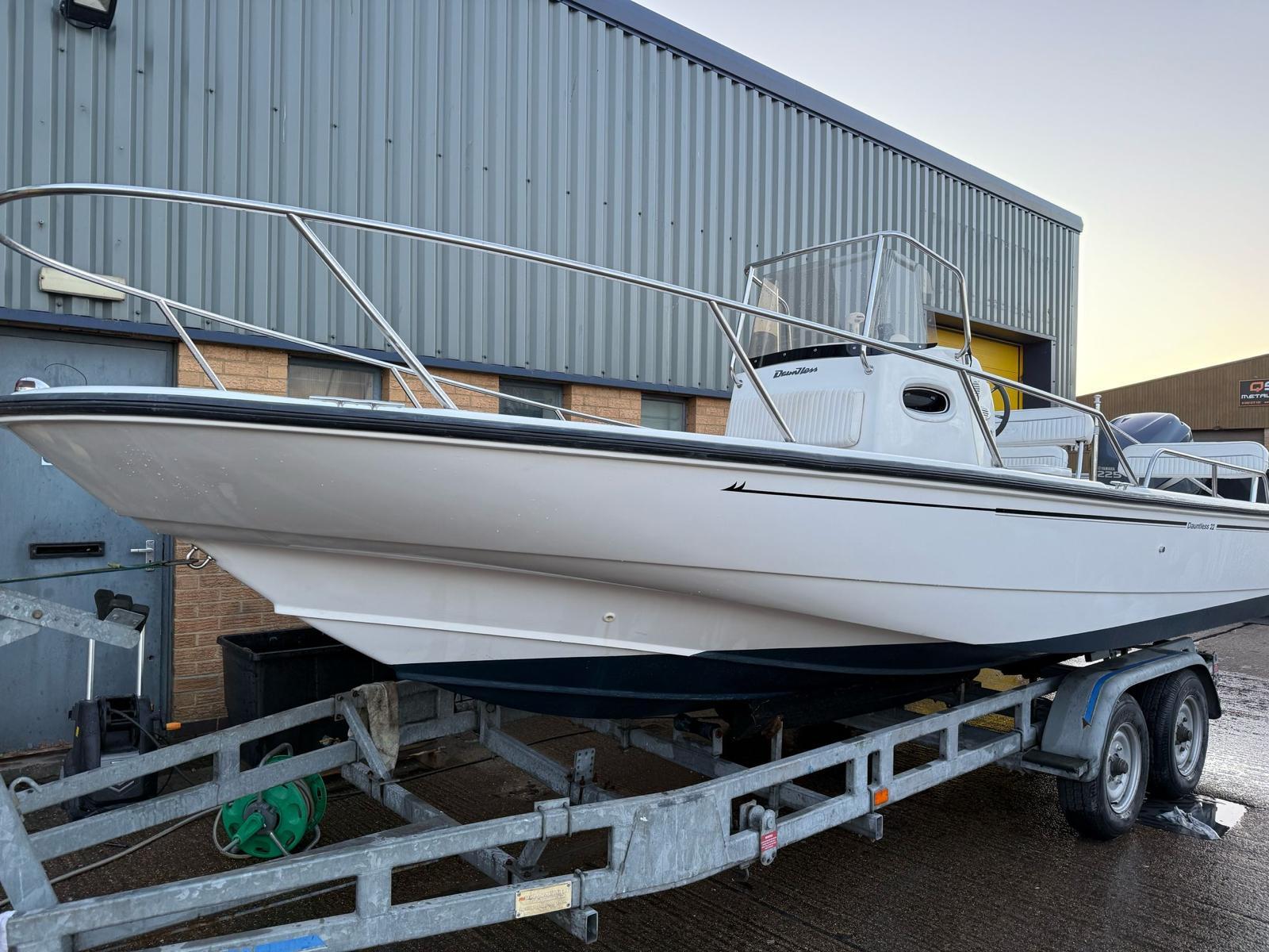 Boston Whaler 22 Dauntless 2001 Boston Whaler 22 Dauntless boat on trailer, parked outside industrial building.