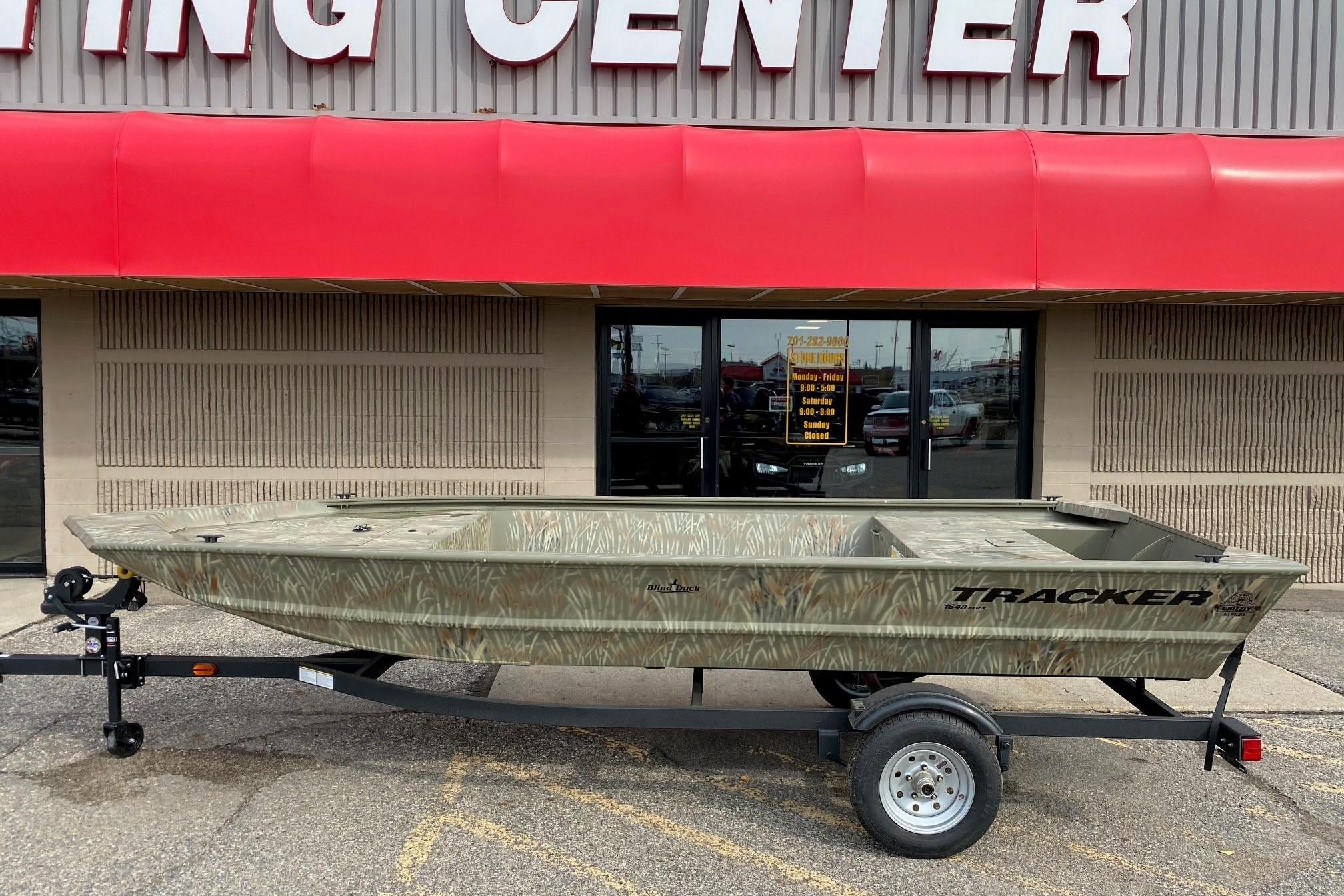 Tracker Grizzly 1648 Jon 2025 Tracker Grizzly 1648 Jon boat on trailer outside a boating center.