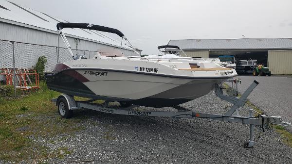 Starcraft SVX 191 OB 2022 Starcraft SVX 191 OB boat on trailer, parked outdoors near a warehouse.