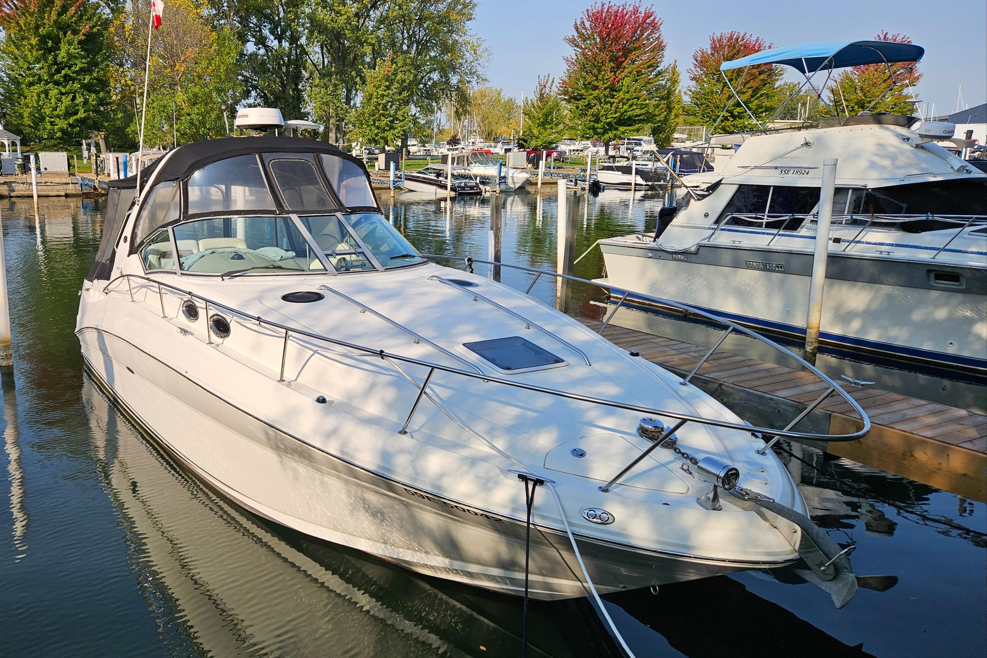Sea Ray 320 Sundancer 2005 Sea Ray 320 Sundancer docked in a marina, surrounded by trees and boats.