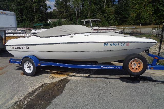 Stingray 180RX 2005 Stingray 180RX boat on a blue trailer, parked outdoors.