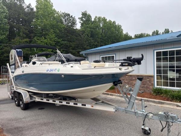 Stingray 212 SC 2021 Stingray 212 SC boat on trailer, parked near a building with trees in the background.