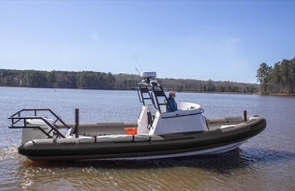 Fluid Watercraft 26 SAR 2025 Fluid Watercraft 26 SAR boat on a calm lake with forested shoreline.