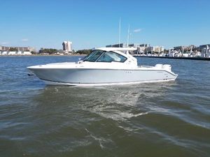 Pursuit DC 326 Dual Console 2023 Pursuit DC 326 Dual Console boat on calm water, cityscape background.