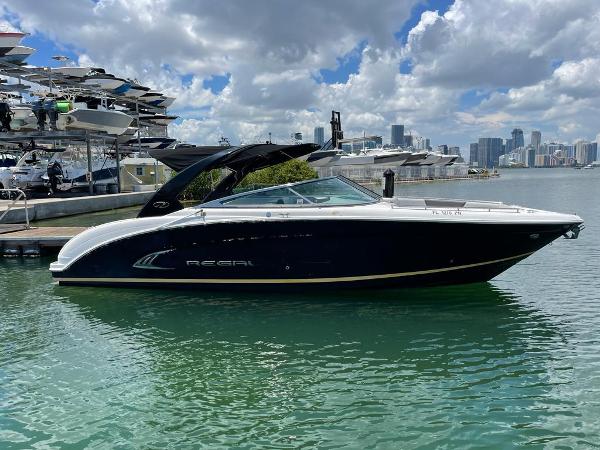 Regal 3200 Bowrider 2013 Regal 3200 Bowrider boat docked in a marina with city skyline.