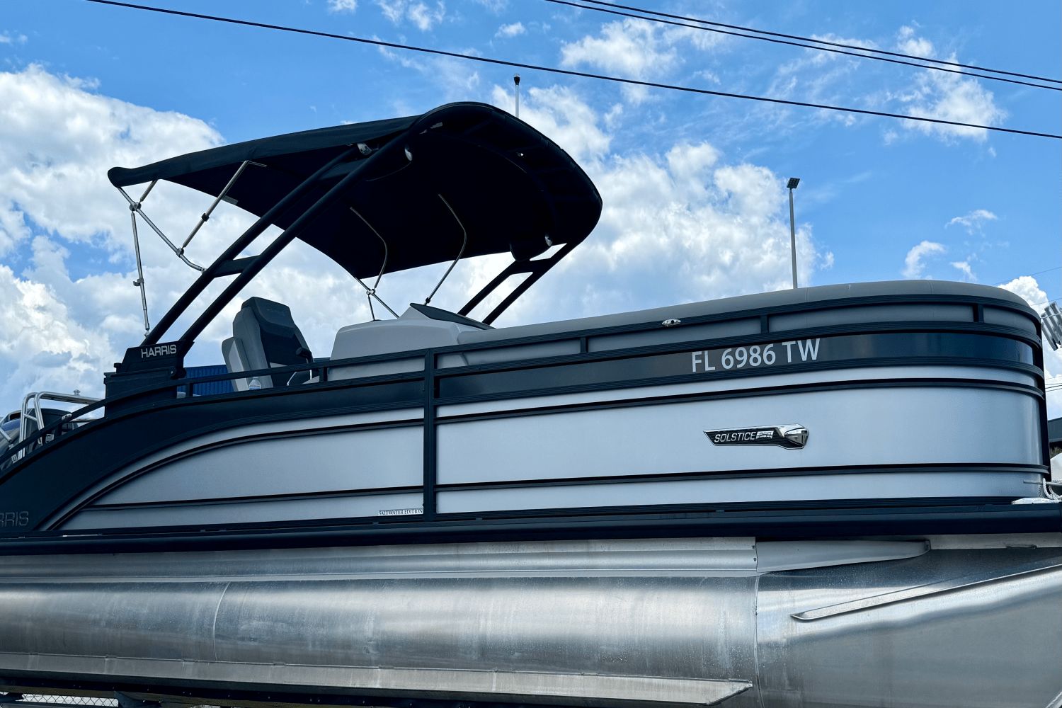 Harris Solstice 250 2024 Harris Solstice 250 pontoon boat with canopy against blue sky.