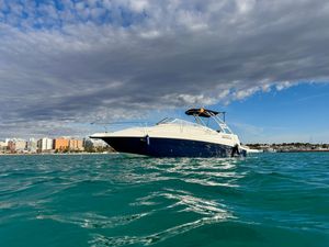 Glastron 249 SSV 1997 Glastron 249 SSV boat on turquoise water with cityscape and cloudy sky backdrop.