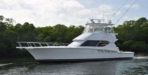 Hatteras 50 Convertible 2002 Hatteras 50 Convertible yacht cruising on calm water near lush greenery.